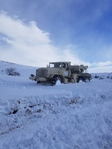 A heavy six-wheel-drive recovery truck parked on a snow-covered hillside.